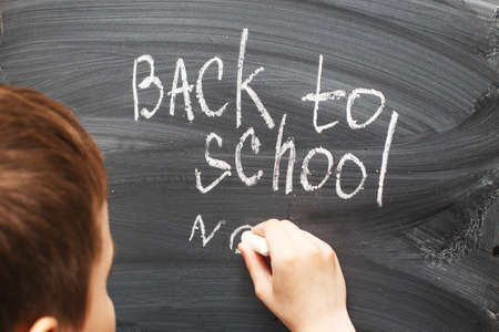 the child writes on the blackboard. Back to school concept backgroundの写真素材