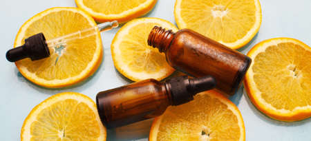 brown glass bottle with a pipette of face serum with vitamin C. Essential oil and orange slices. Health and beauty concept. Organic Natural Cosmetics. bannerの写真素材