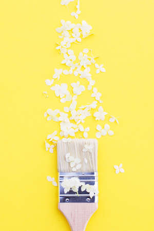white hydrangea flowers and paint brush on a yellow background with copy space. Flat lay.の写真素材