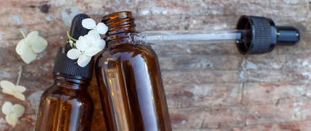 brown glass bottles with dropper of essential oil and white flowers hydrangea on old wooden shabby background. concept of natural organic cosmetics, beauty spa aroma herbal product. bannerの写真素材