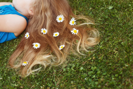 Healthy red hair on a green grass background with chamomile flowers.の写真素材