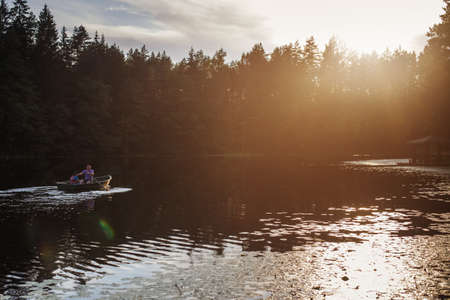 dad and son are sailing on a boat on the lake for fishing.の写真素材