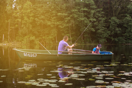 Father and son fishing on rural lake at sunset on a boat.の写真素材