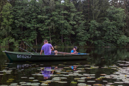 Father and son fishing on rural lake at sunset on a boat.の写真素材
