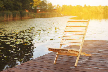Wooden dock with lounge chair on pier on the calm lake in the middle of the forest.の写真素材