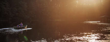 dad and son are sailing on a boat on the lake for fishing. bannerの写真素材