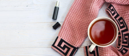A cup of hot tea, knitted sweater, and perfume on a wooden light table. banner. winter morning conceptの写真素材
