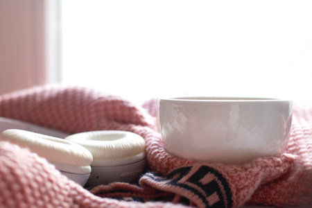 Cozy winter morning at home. Hot tea or coffee, knitted sweater and headphones near the window. Lifestyle and music conceptの写真素材