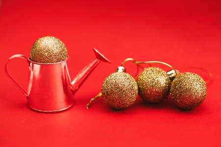 Gold balls and decorative watering can on a red background.の写真素材