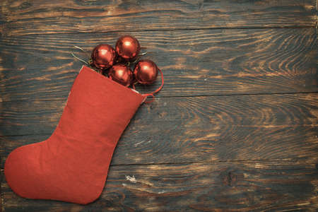 red balls and toys with Christmas sock on a wooden background.の写真素材