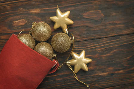 Gold balls and toys with Christmas sock on a wooden background.の写真素材