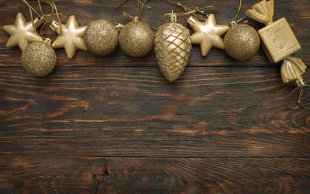 Gold Christmas balls and toys on a wooden background.