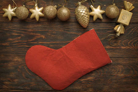 Gold balls and toys with Christmas sock on a wooden background.の写真素材