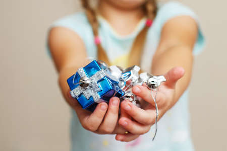 girl's hands hold the holding a christmas toys a blue gift box.の写真素材