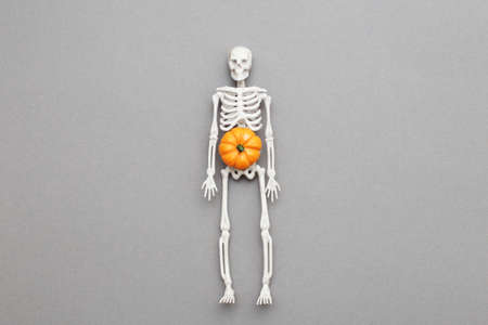 skeleton with pumpkin on gray background. halloween concept.の写真素材