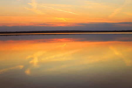 Reflection of a beautiful golden sunset over the waterの写真素材