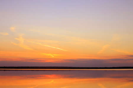Reflection of a beautiful golden sunset over the waterの写真素材