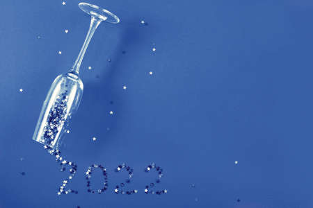 Champagne glass with star shaped sequins in the form of inscription 2021 on a blue backgroundの写真素材