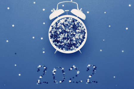 Alarm clock and star shaped confetti on blue background. 2022の写真素材