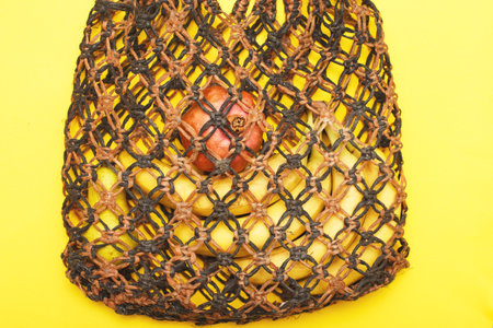 brown string bag with ripe fruits on a yellow background.の写真素材