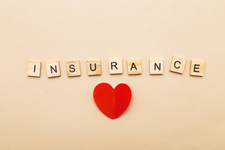 inscription insurance on a beige background made by wooden blocks with red heart.の写真素材