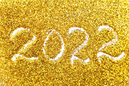 the number 2022 written on golden confetti. christmas or new year backgroundの写真素材