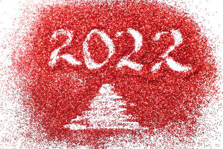 a finger drawn christmas tree and number 2022 on shiny red confetti backgroundの写真素材