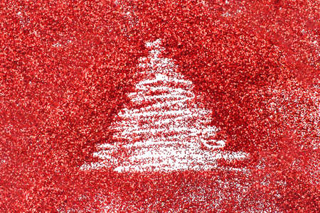 a finger drawn christmas tree on shiny red confetti backgroundの写真素材