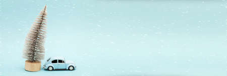 Miniature blue car with a christmas tree on a blue background. bannerの写真素材