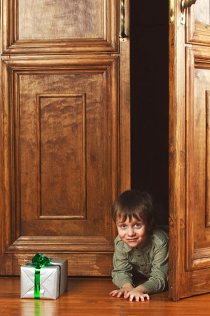 child peeking from behind the door of the giftの写真素材