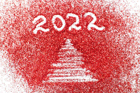 a finger drawn christmas tree and number 2022 on shiny red confetti backgroundの写真素材