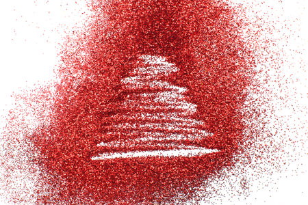 a finger drawn christmas tree on shiny red confetti backgroundの写真素材