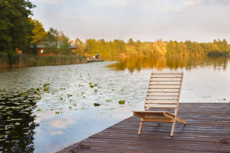 Wooden dock with lounge chair on pier on the calm lake in the middle of the forestの写真素材