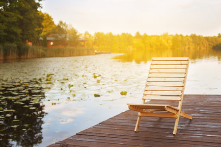 Wooden dock with lounge chair on pier on the calm lake in the middle of the forestの写真素材