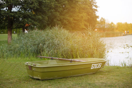 a boat on the grass of the shore of calm lakeの写真素材