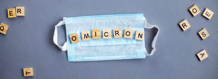 word omicron made by wooden blocks with medical mask on gray background. bannerの写真素材