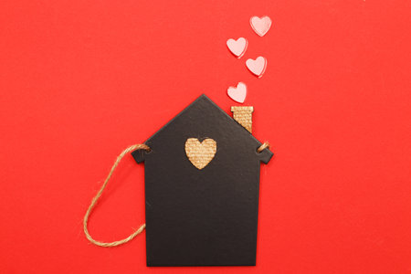small toy house with red hearts from pipe on red background. Concept of love, family.の写真素材