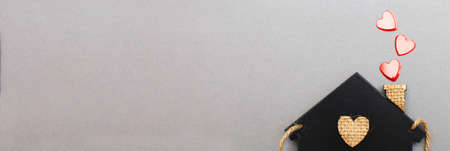 small toy house with red hearts from pipe on gray background. Concept of love, family.の写真素材