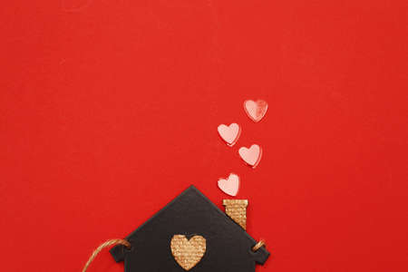 small toy house with red hearts from pipe on red background. Concept of love, family.の写真素材