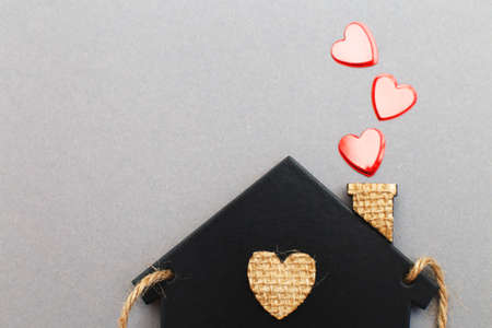small toy house with red hearts from pipe on gray background. Concept of love, family.の写真素材