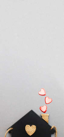 small toy house with red hearts from pipe on gray background. Concept of love, family.の写真素材