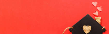 small toy house with red hearts from pipe on red background. Concept of love, family.の写真素材