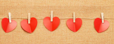 red hearts on clothes pin on brown textile background. bannerの写真素材