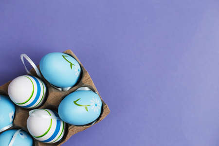 top view easter colorful handmade painted blue eggs in a box on purple backgroundの写真素材