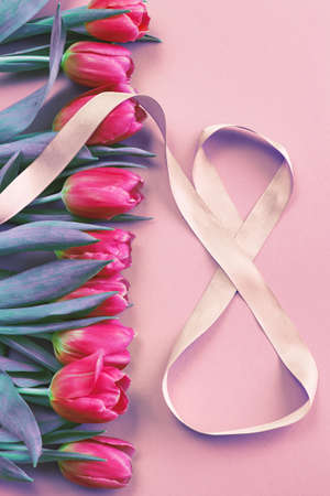 8 March card design with a pink tulips and ribbon in the shape of number eight. International Women's Dayの写真素材