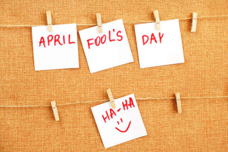 sticker with smiley hanging on the pin and the inscription april fools day on brown textile background. Copy space for textの写真素材