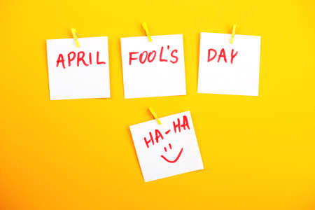 sticker with smiley hanging on the pin and the inscription april fools day on yellow background. Copy space for textの写真素材