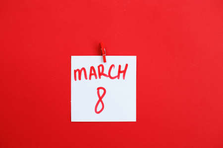 sticker with text March 8 hanging on the pin on the red background. Copy space for textの写真素材