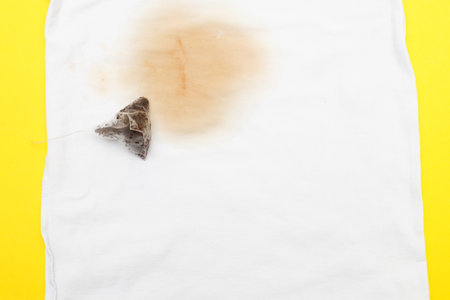 spilled tea stain on white clothes with a tea bag next to itの写真素材