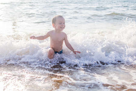 a little boy having fun in the sea on the waves.の写真素材